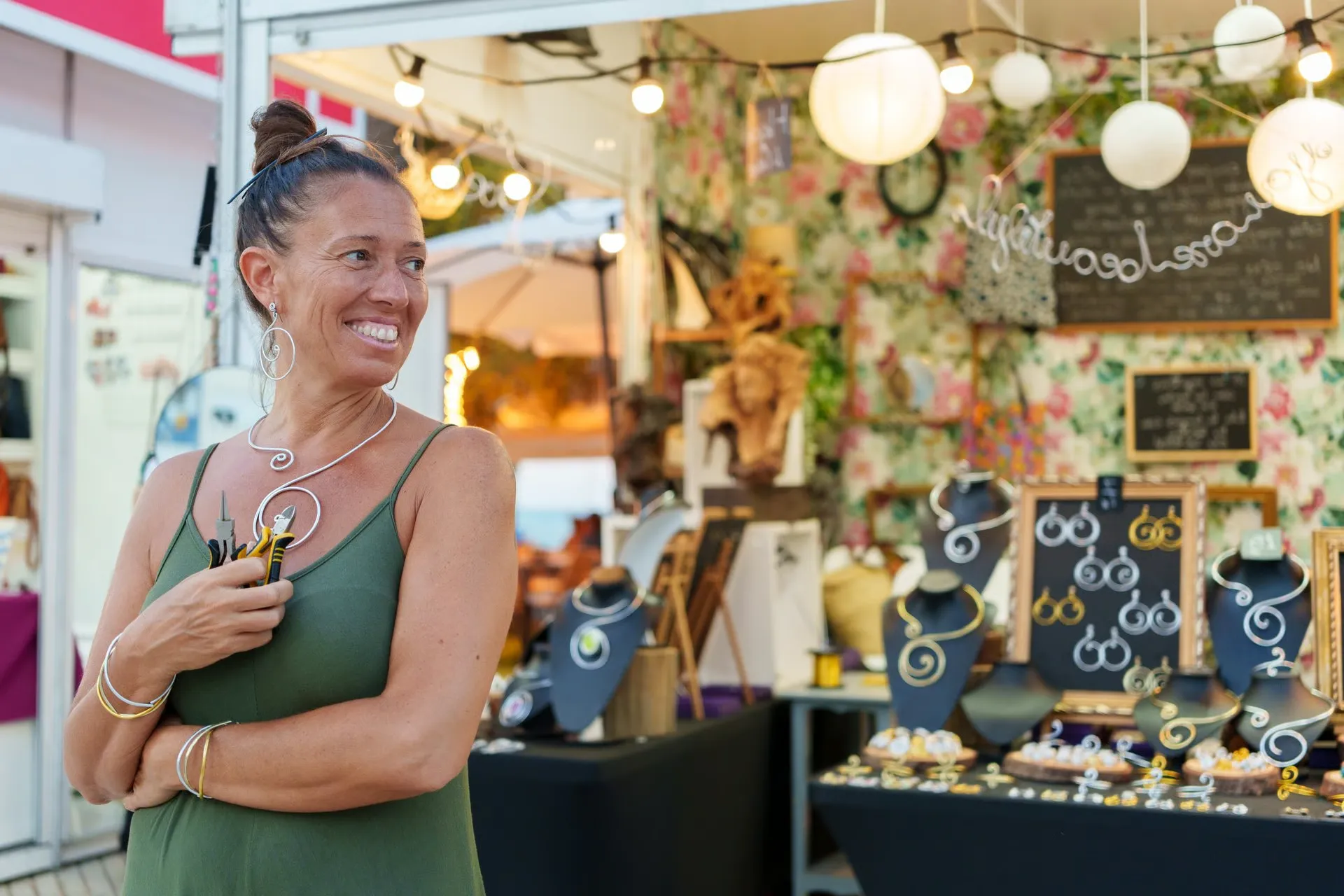 Smiling jewelry maker showing handmade necklaces and earrings